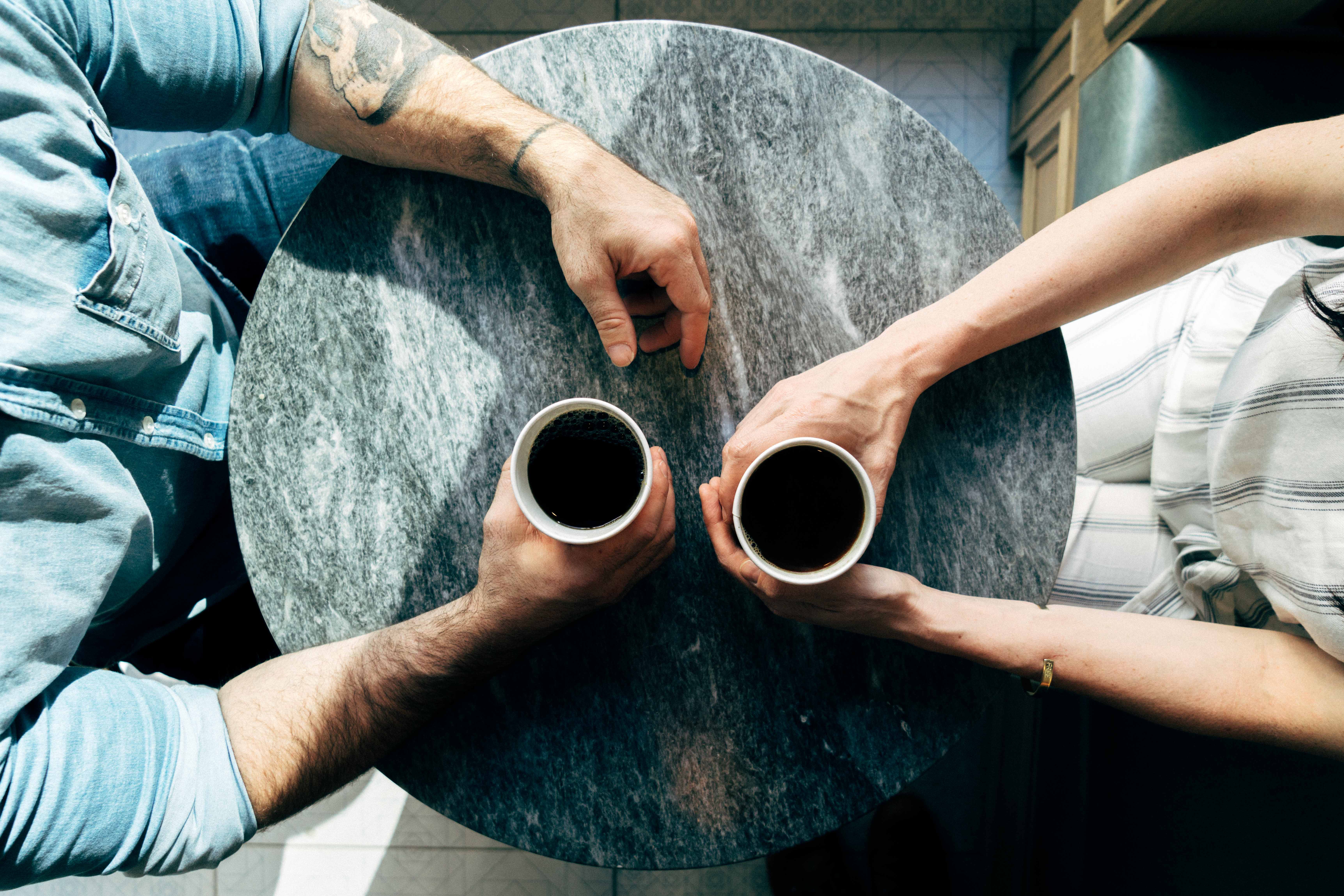 Photo of two coffee cups, people talking