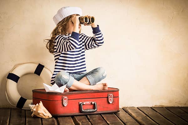 Young girl dressed as sailor using binoculars